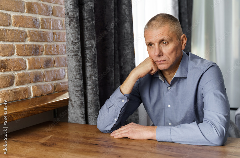 Portrait of a pensive middle-aged man sitting at a table. Portrait of a pensive middle-aged man sitting at a table.