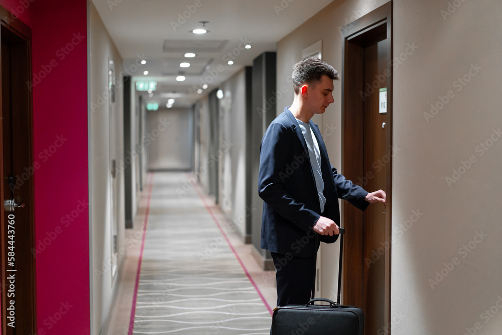 A man with a suitcase opens the door of a hotel room a businessman on a trip travel concept