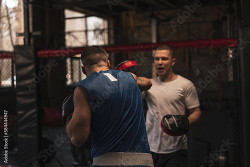 Boxer Practices His Punches with His Coach in the Boxing Gym © Guys Who Shoot