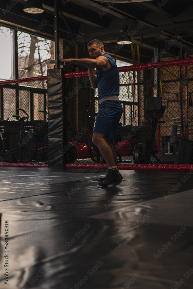 Fototapeta premium A boxer in the gym who fights with the shadow practices punches