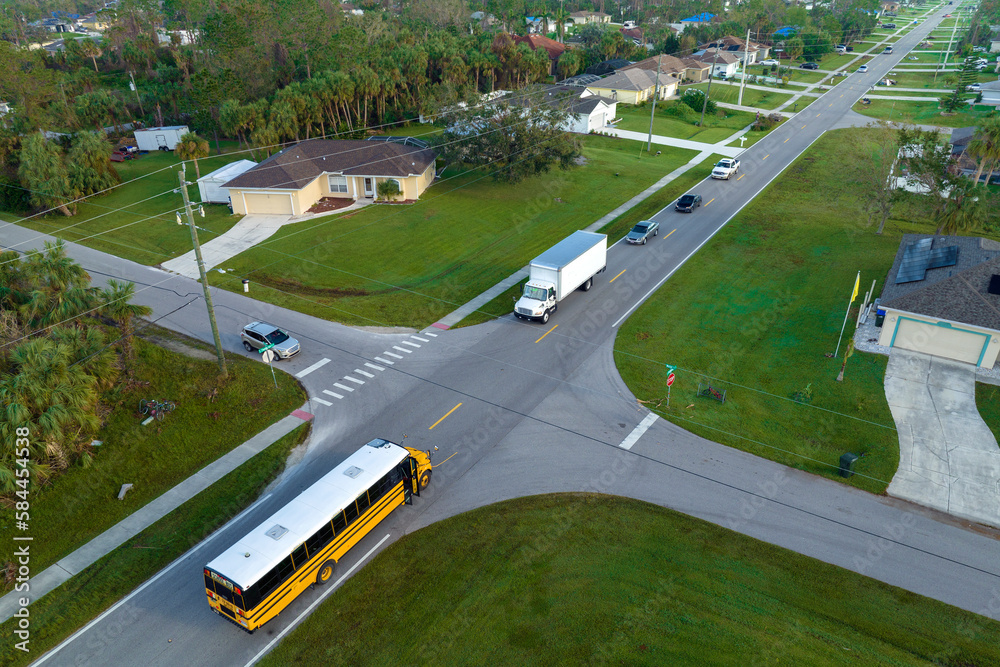 Top view of classical american yellow school bus picking up kids at rural town street stop for their lessongs in early morning. Public transport in the USA Top view of classical american yellow school bus picking up kids at rural town street stop for their lessongs in early morning. Public transport in the USA