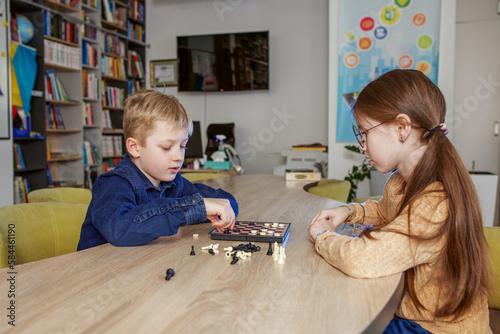 Children play game of checkers. Concept of education, hobby and leisure.