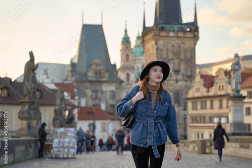 Obraz na płótnie Female traveller tourist on the Charles Bridge in Prague, Czezh Repubic. Stylish beautiful young woman earing black hat. Elegant retro lady fine art portrait. w salonie