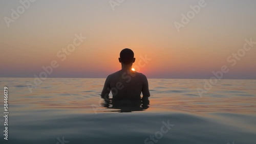 A man alone in the sea watches the sunset, in Koh Chang, Thailand