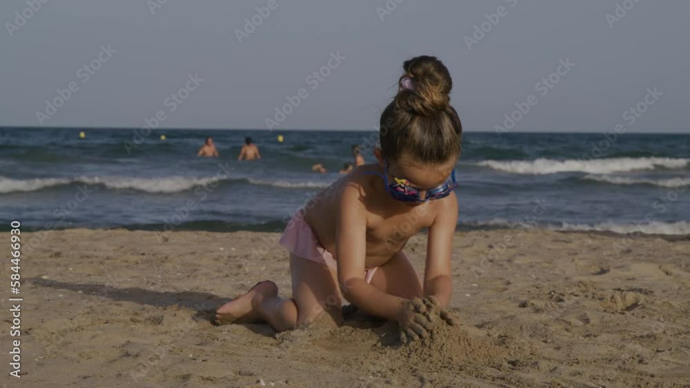 Child Playing Sand On The Sea Beach. Little Girl Builds Sand castle By Himself On The Seashore. Kid Playing Sand near the ocean water. Summer vacation concept. High quality 4k footage Child Playing Sand On The Sea Beach. Little Girl Builds Sand castle By Himself On The Seashore. Kid Playing Sand near the ocean water. Summer vacation concept. High quality 4k footage
