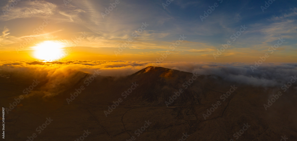 Dramatic high level aerial panoramic view of the rare low level cloud, mist or fog over Calderon Hondo volcanic crater at sunset near Corralejo in Fuerteventura Canary Islands Spain