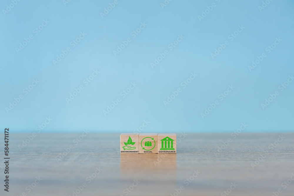 Obraz premium Wooden cubes with abbreviation ESG icons on blue background. ESG concept of environmental, social and governance. Sustainable corporation development. Copy space.