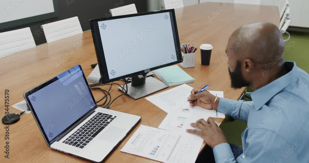 African american businessman in office using computer and laptop, copy space on screens, slow motion African american businessman in office using computer and laptop, copy space on screens, slow motion