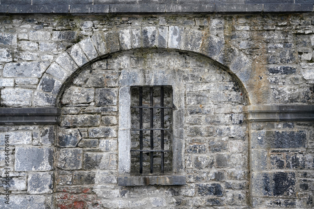            prison bars on window in old stone wall
