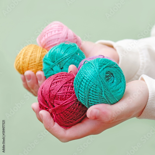 multi-colored balls of threads in hands. balls of thread for needlework in the hands of a female child