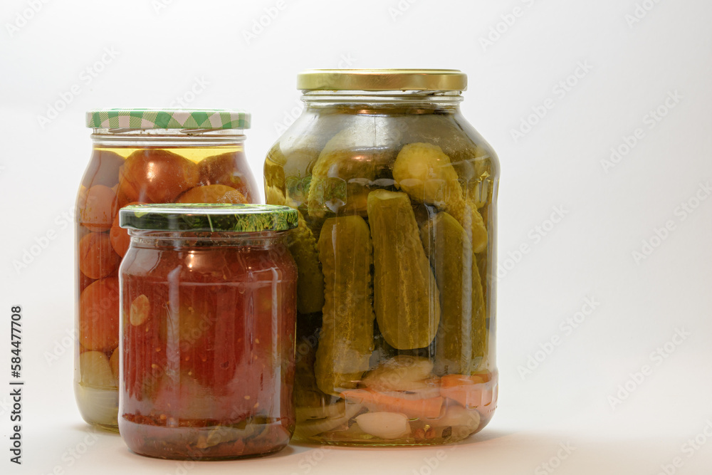 Composition of 3 jars with preservation of different sizes, on a white background. Edible prepared vegetables, canned food, pickled cucumbers, pickled tomatoes. Composition of 3 jars with preservation of different sizes, on a white background. Edible prepared vegetables, canned food, pickled cucumbers, pickled tomatoes.