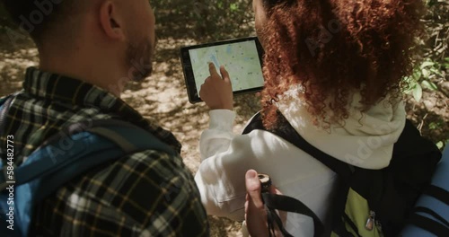 Wallpaper Mural Happy african american couple wearing backpack, using tablet in forest, slow motion Torontodigital.ca