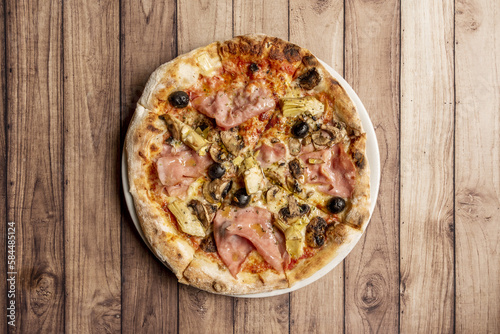 Pizza capricciosa is a style of pizza from Italian cuisine prepared with mozzarella cheese, oven-roasted Italian ham, artichokes, tomato and some edible mushroom that is usually mushroom