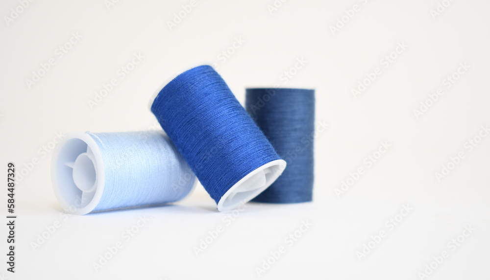Three spools of blue yarn in different shades on a white background Three spools of blue yarn in different shades on a white background