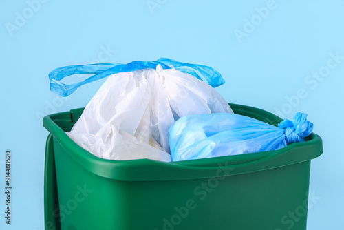 Recycle bin with garbage bags on blue background, closeup