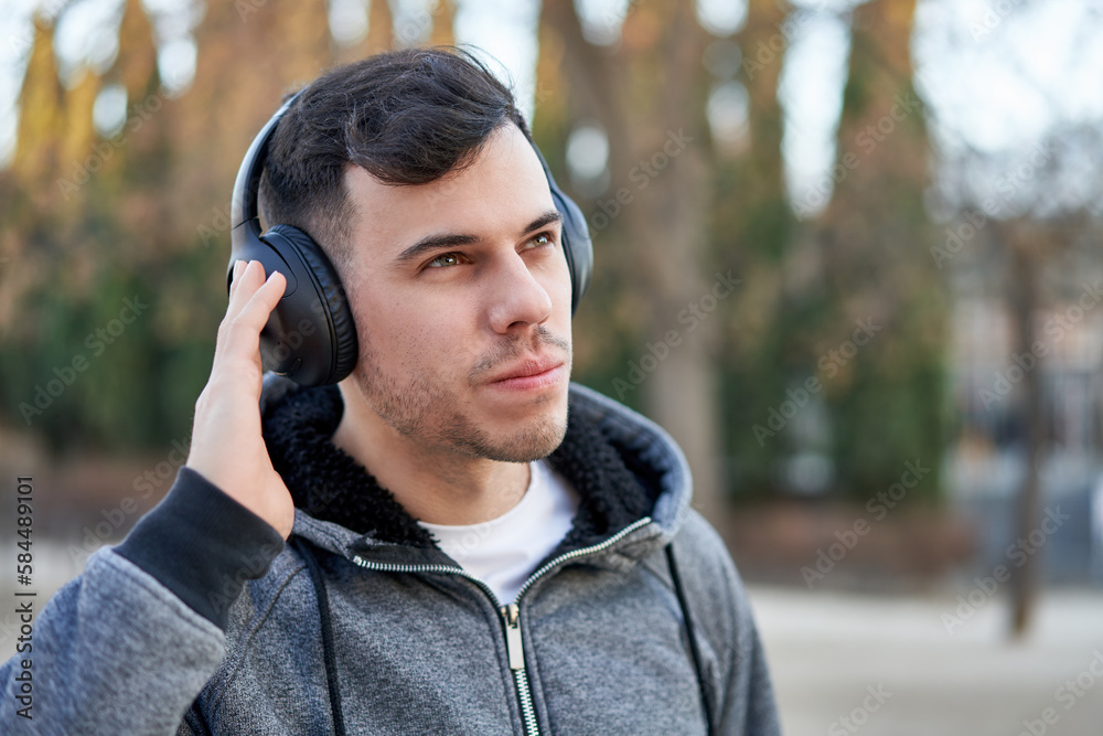 Caucasian young man enjoying music in the park with his headphones on. Caucasian young man enjoying music in the park with his headphones on.