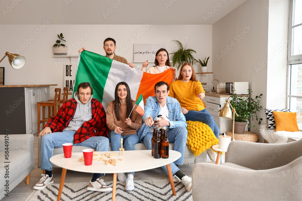 Group of friends with soccer ball and flags of Ireland at home