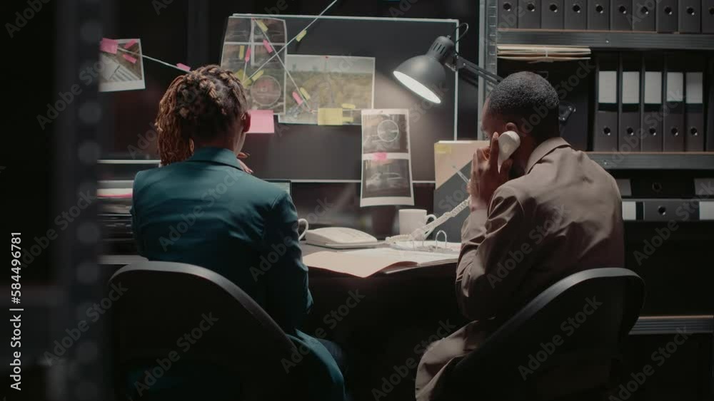 Private investigators examining surveillance photos and reading case file in police agency office. Detective looking at suspicious evidence on laptop, assistant studying criminal records.