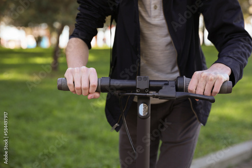 Man riding modern electric scooter in park, closeup