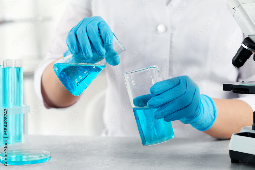 Scientist working with beakers in laboratory, closeup Scientist working with beakers in laboratory, closeup