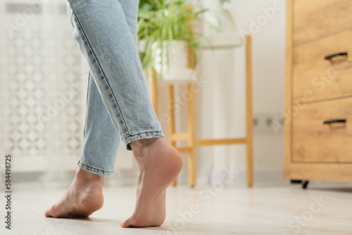 Woman stepping barefoot in room at home, closeup with space for text. Floor heating