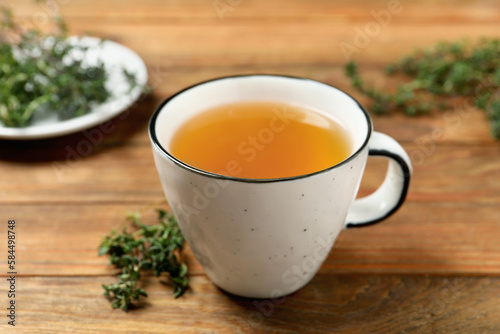 Aromatic herbal tea with thyme on wooden table, closeup