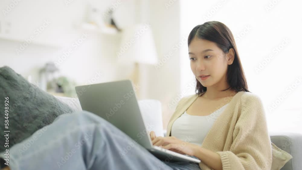 Young asian woman using laptop while seated on couch at home Young asian woman using laptop while seated on couch at home