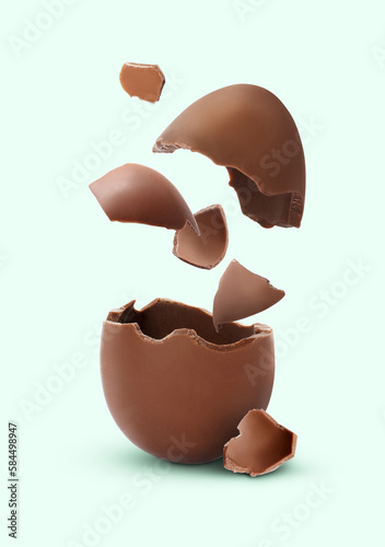Exploded milk chocolate egg on pale light blue background