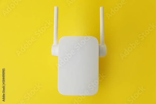 New modern Wi-Fi repeater on yellow background, top view
