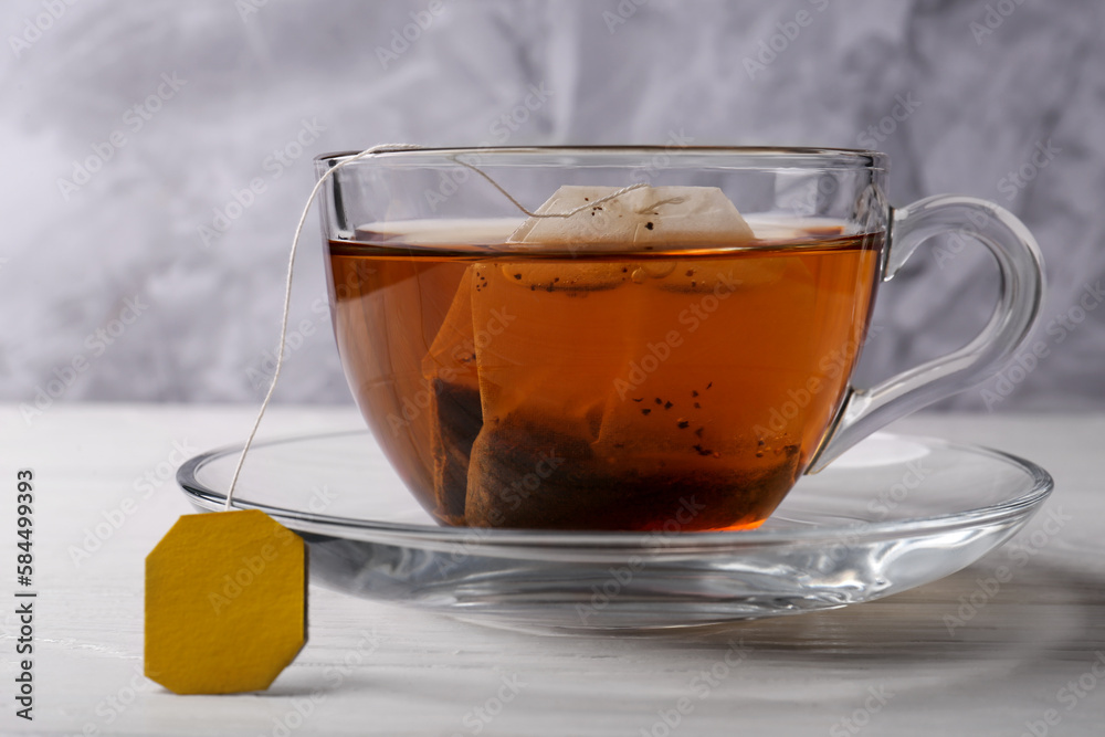 Tea bag in glass cup on white wooden table, closeup
