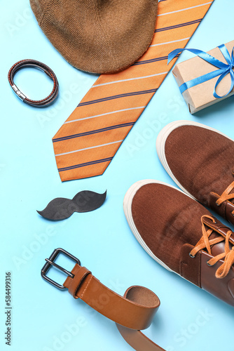 Paper mustache with gift and male accessories on blue background. Father's Day celebration