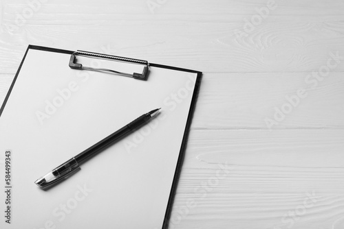 New clipboard with sheet of blank paper and pen on white wooden table, above view. Space for text