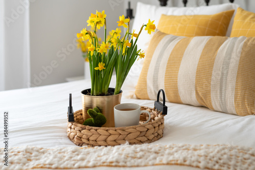 Cheerful yellow flowers and tea on a tray in a stylish bedroom