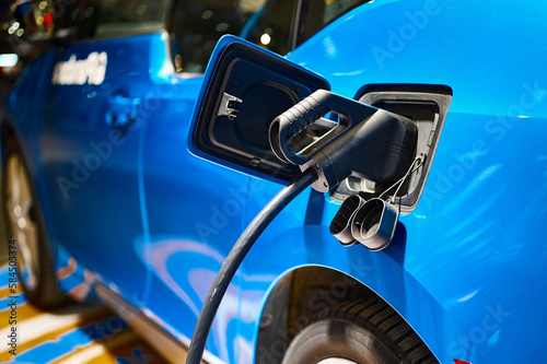 Charging electric blue automobile with plug at power station