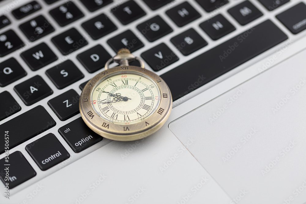 A pocket watch is on the computer keyboard