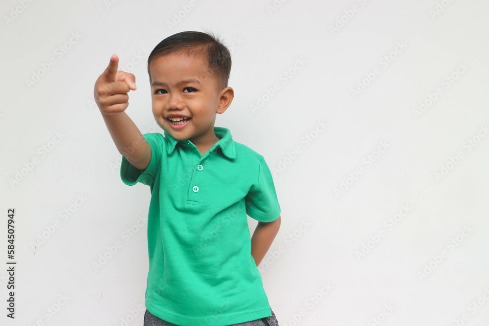 Portrait of a happy little Asian boy smiling while pointing , isolated on the white background Portrait of a happy little Asian boy smiling while pointing , isolated on the white background