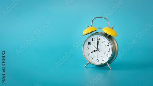 Retro silver alarm clock. 7:00, am, pm. Blue background.