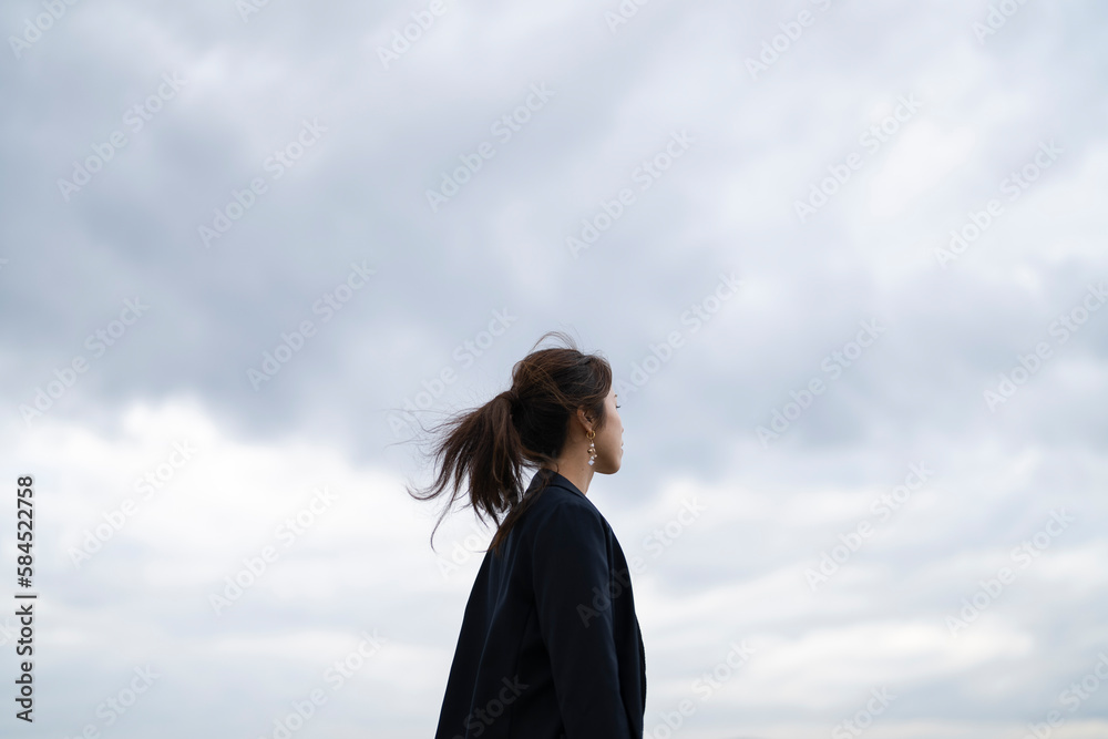 曇りの日の海にいるポニーテールの女性