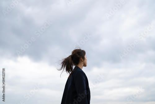曇りの日の海にいるポニーテールの女性