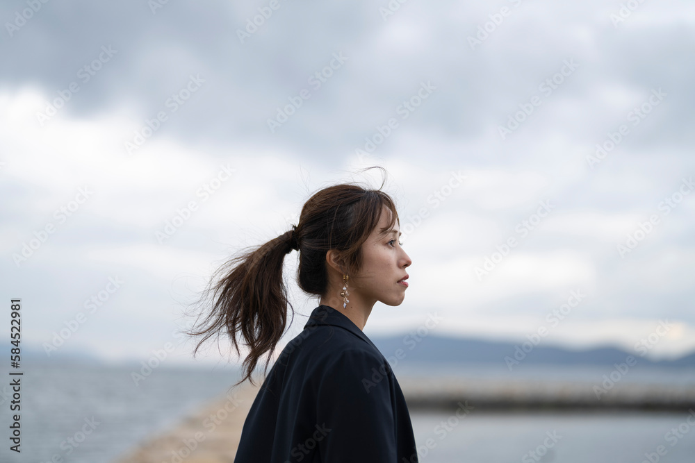 曇りの日の海にいるポニーテールの女性 曇りの日の海にいるポニーテールの女性