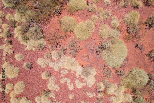 Looking down from a lower angle seeing only the red Australian outback dirt and speckles of bushes in an arid land.