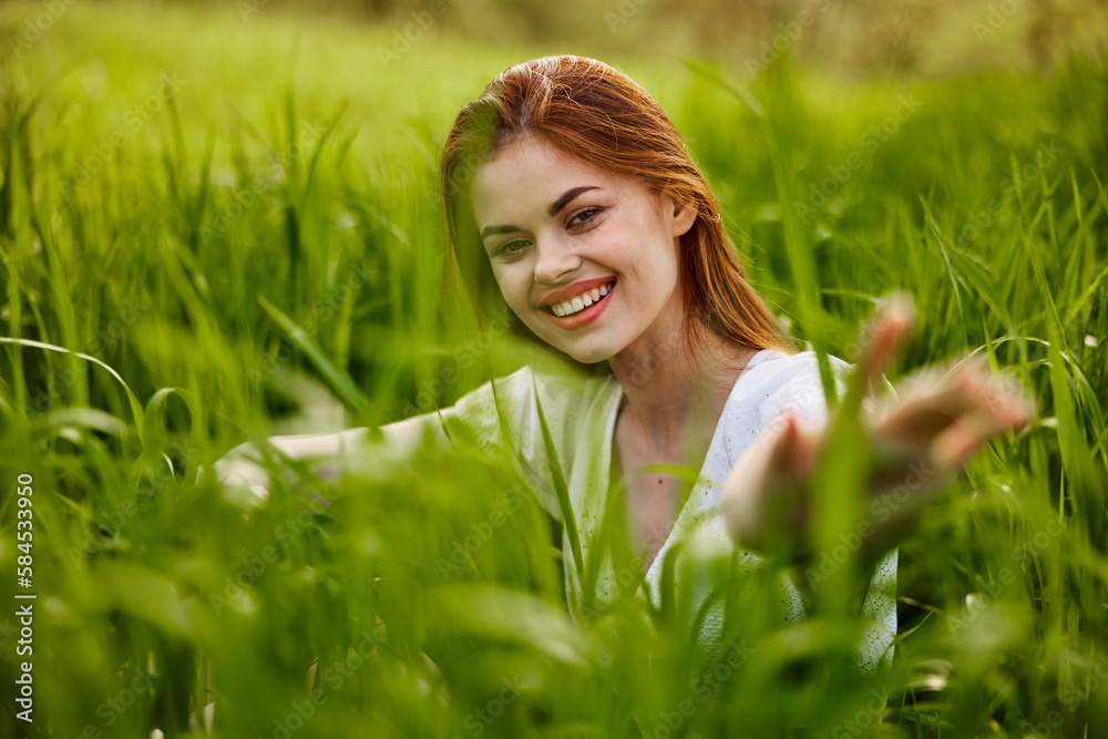 portrait of a broadly smiling woman sitting in tall grass and holding out her hands to the camera portrait of a broadly smiling woman sitting in tall grass and holding out her hands to the camera