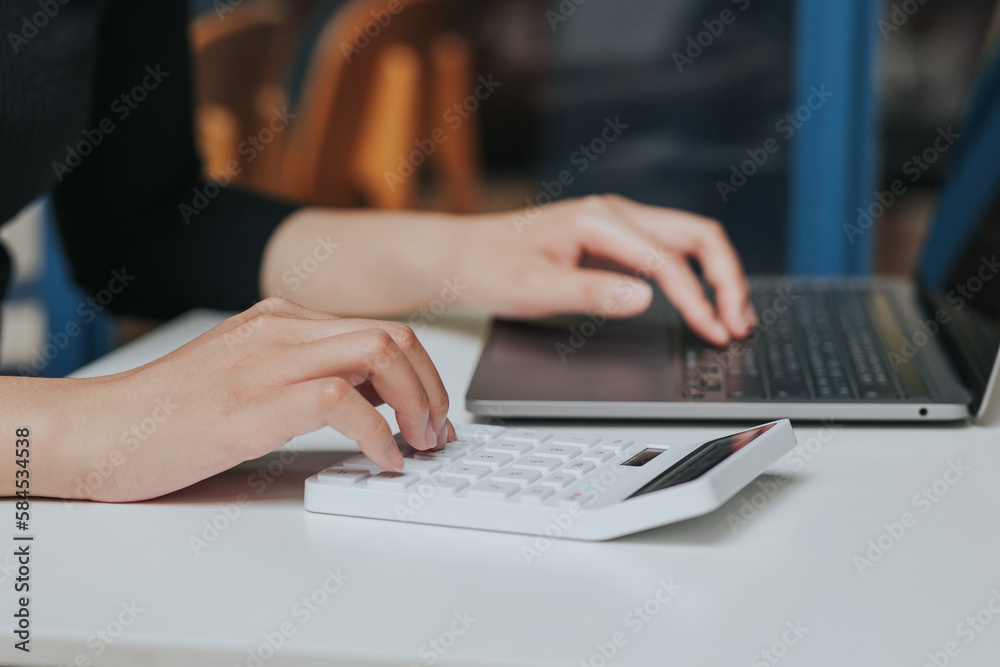 Young Asian woman using smartphone and laptop working remotely at coffee shop. Young Asian woman using smartphone and laptop working remotely at coffee shop.