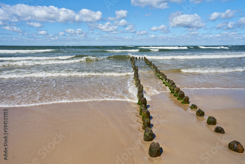 Baltic Sea - blue sky, wave sea and wooden waterbreak.