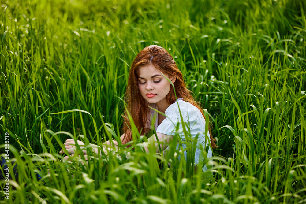 sad woman sitting in tall green grass on a sunny day sad woman sitting in tall green grass on a sunny day