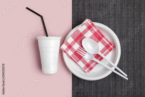 Plastic white crockery and cutlery on a two-tone background. Studio shot, close-up, top view.