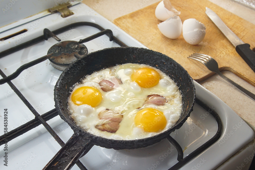 Cooking scrambled eggs in a frying pan in the kitchen on a gas stove. Cooking scrambled eggs in a frying pan in the kitchen on a gas stove.