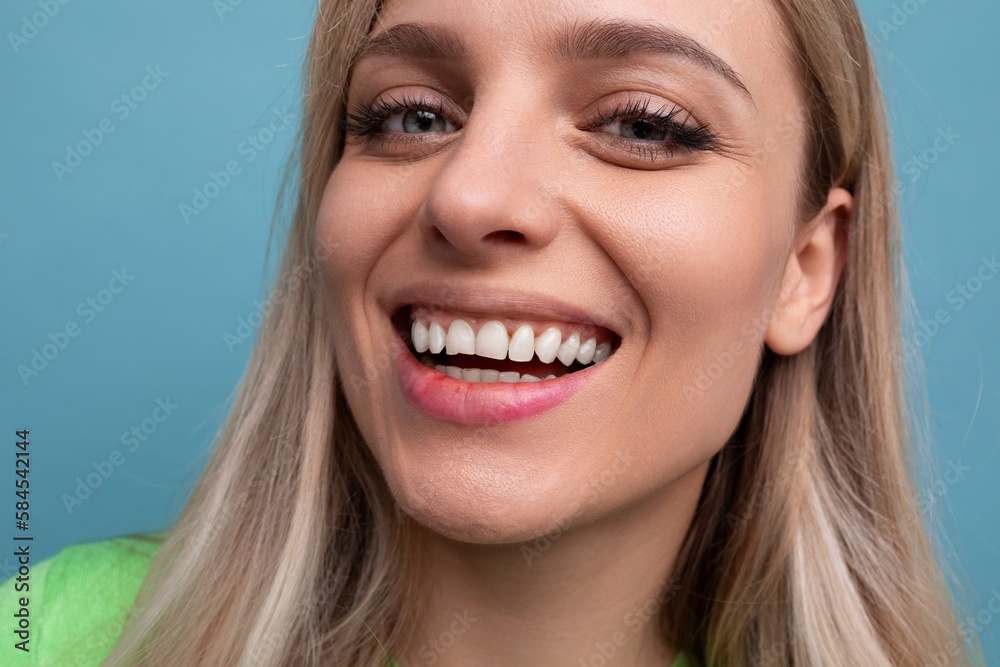 close-up of a healthy young blond woman with straight teeth on a blue background close-up of a healthy young blond woman with straight teeth on a blue background