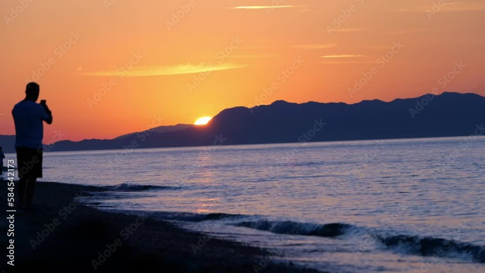 Tourists During Sunset In Rhodes Beach, Greece Island. Static Shot Tourists During Sunset In Rhodes Beach, Greece Island. Static Shot