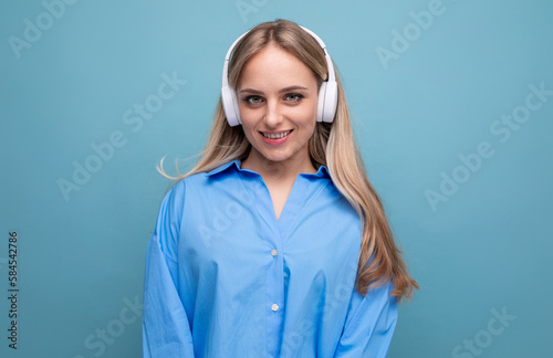 smiling blond girl in casual shirt listening to podcast in big headphones